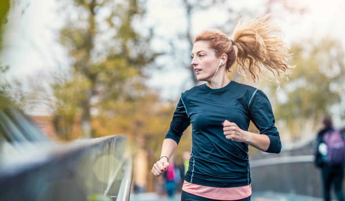 A woman jogging outdoors along a lakeside path