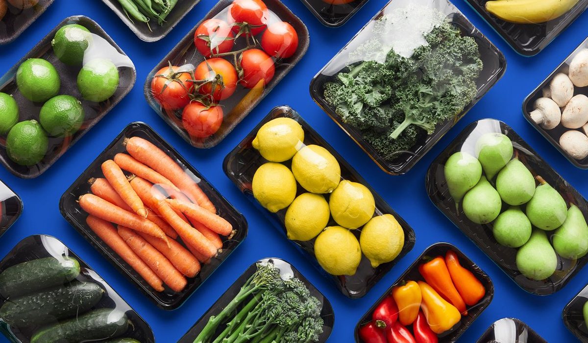 A colourful spread of vegetables, fruit, nuts and fish on a dark surface