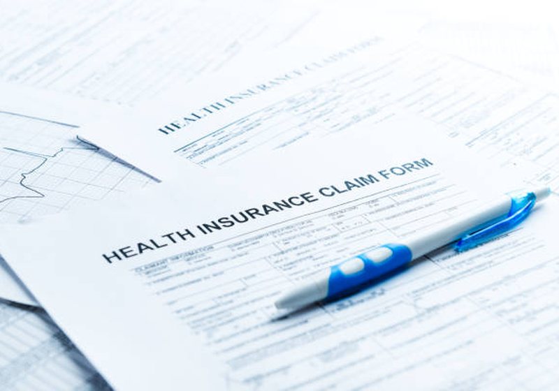 Health insurance paperwork and a laptop on a desk