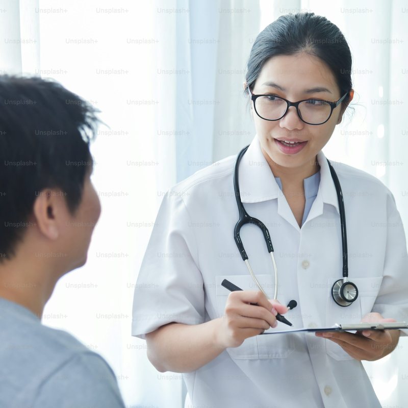 A clinician smiling while reviewing notes with a patient in a bright consultation room