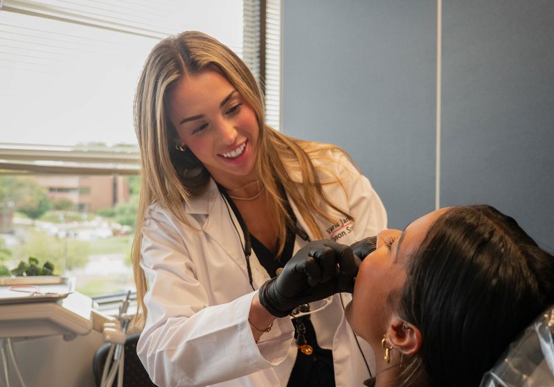 A dental professional examining a smiling patient in a dental chair