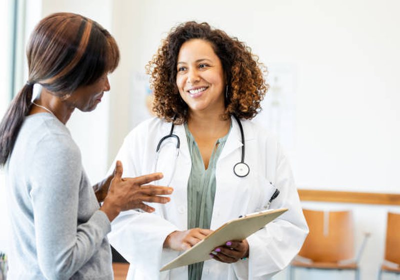 A doctor in a white coat talking with a patient during a general health consultation